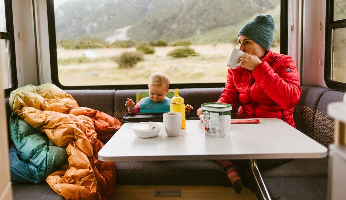 A mom and her baby sitting at a table in a camper vehicle