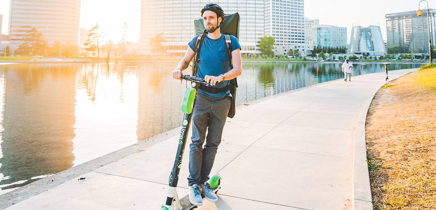 Man on electric scooter with an Oru Kayak Pack for Inlet