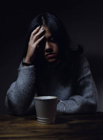 Girl in a grey top with her hand on her head