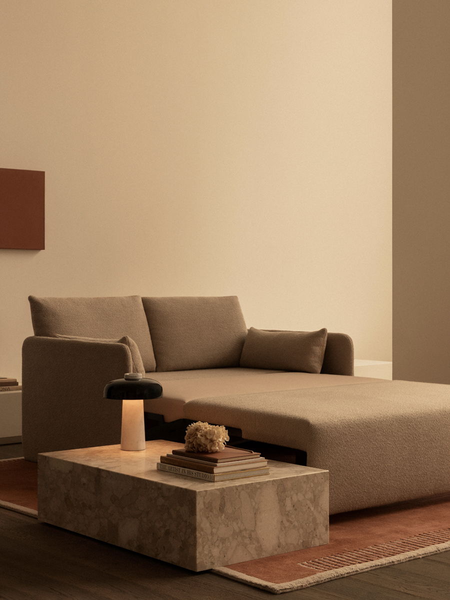 A modern living room featuring a brown Offset sofa bed by Audo Copenhagen and a Pinth coffee table.
