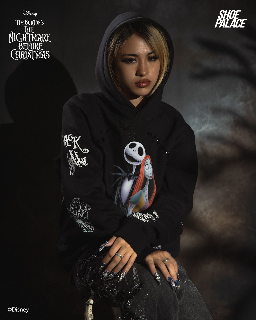 Person wearing a hoodie featuring Jack Skellington and Sally from The Nightmare Before Christmas.