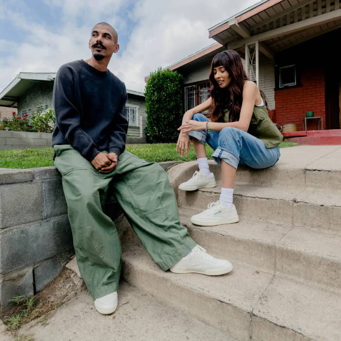 male and female model wearing reebok sneakers in front of hosue