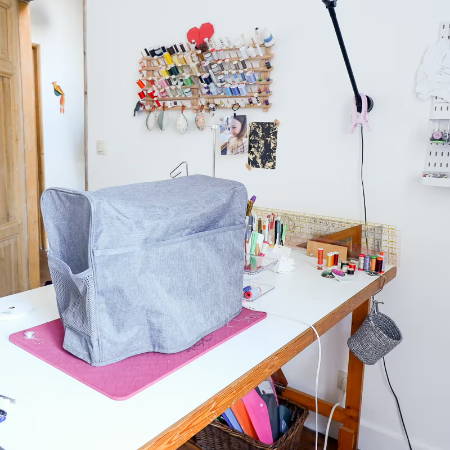sewing room with a sewing machine on a table covered with a machine cover