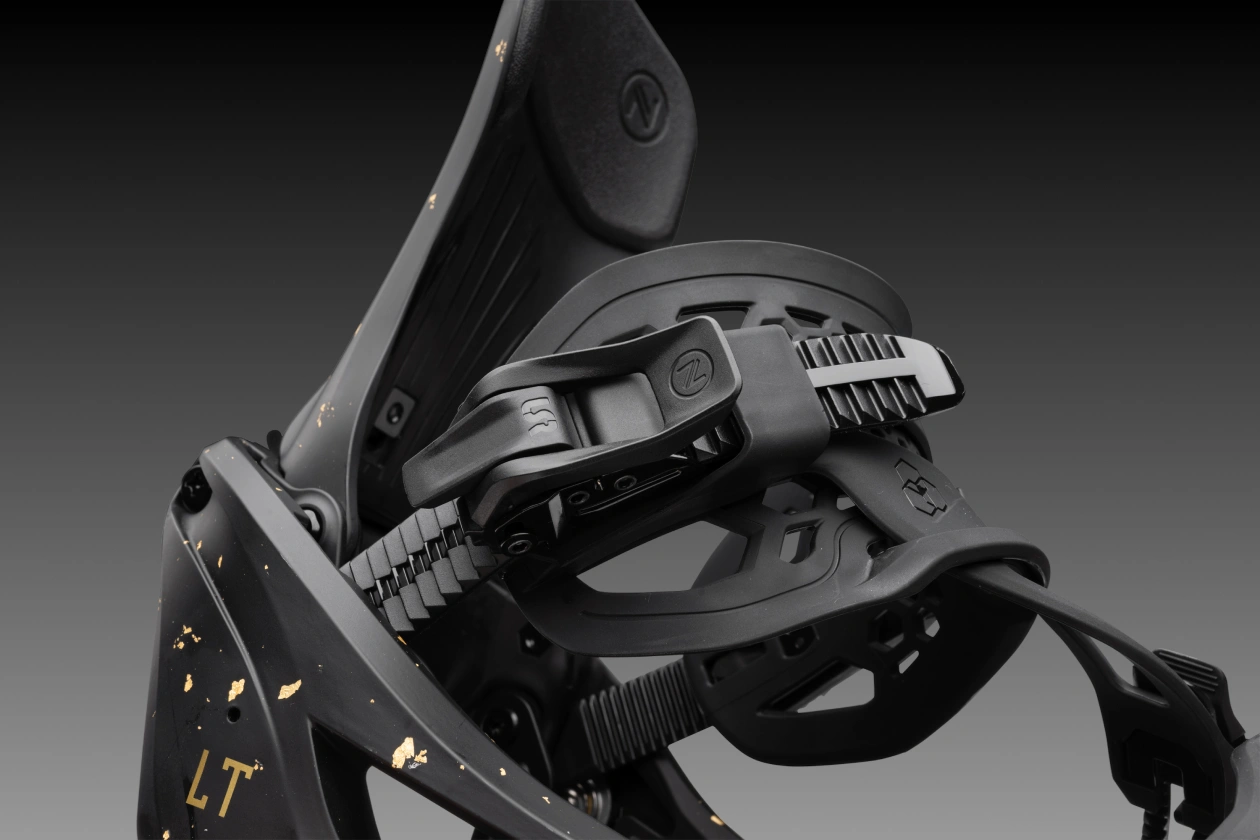 Black snowboarding binding on a dark background with gold accents.