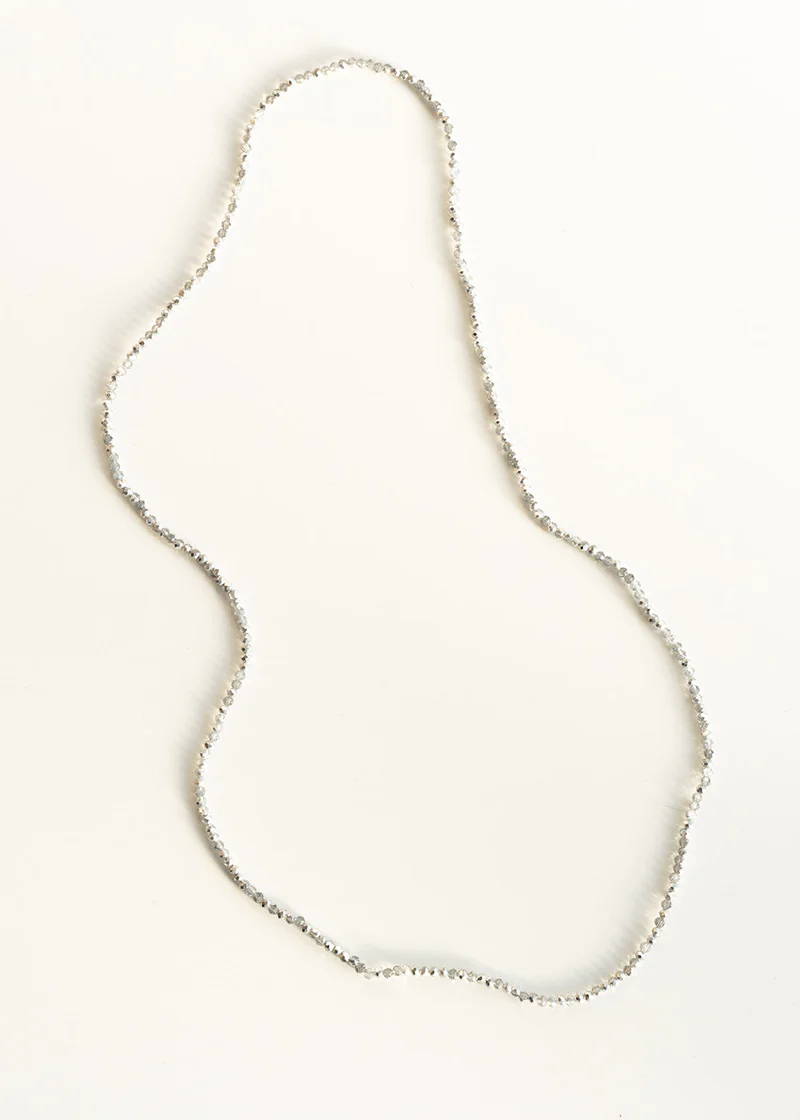 A silver small beaded necklace on a white background