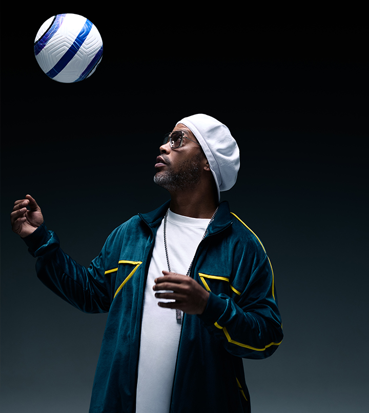 A person in sunglasses and a beanie posing thoughtfully against a dark background.