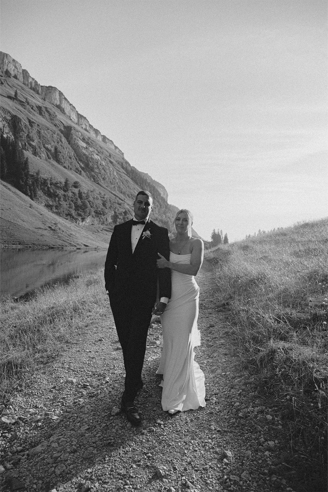 Black and white photo of a couple walking along a scenic mountain path.