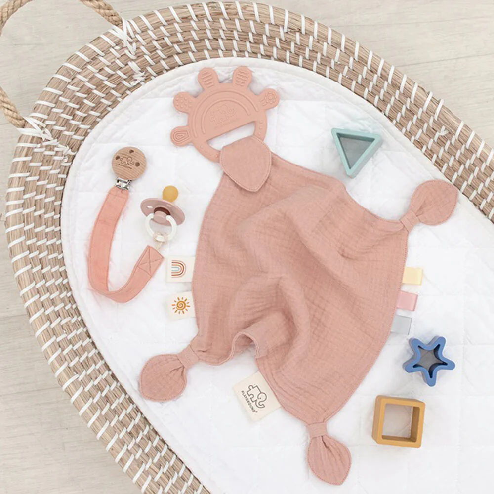 Soft toys and accessories arranged on a textured surface.