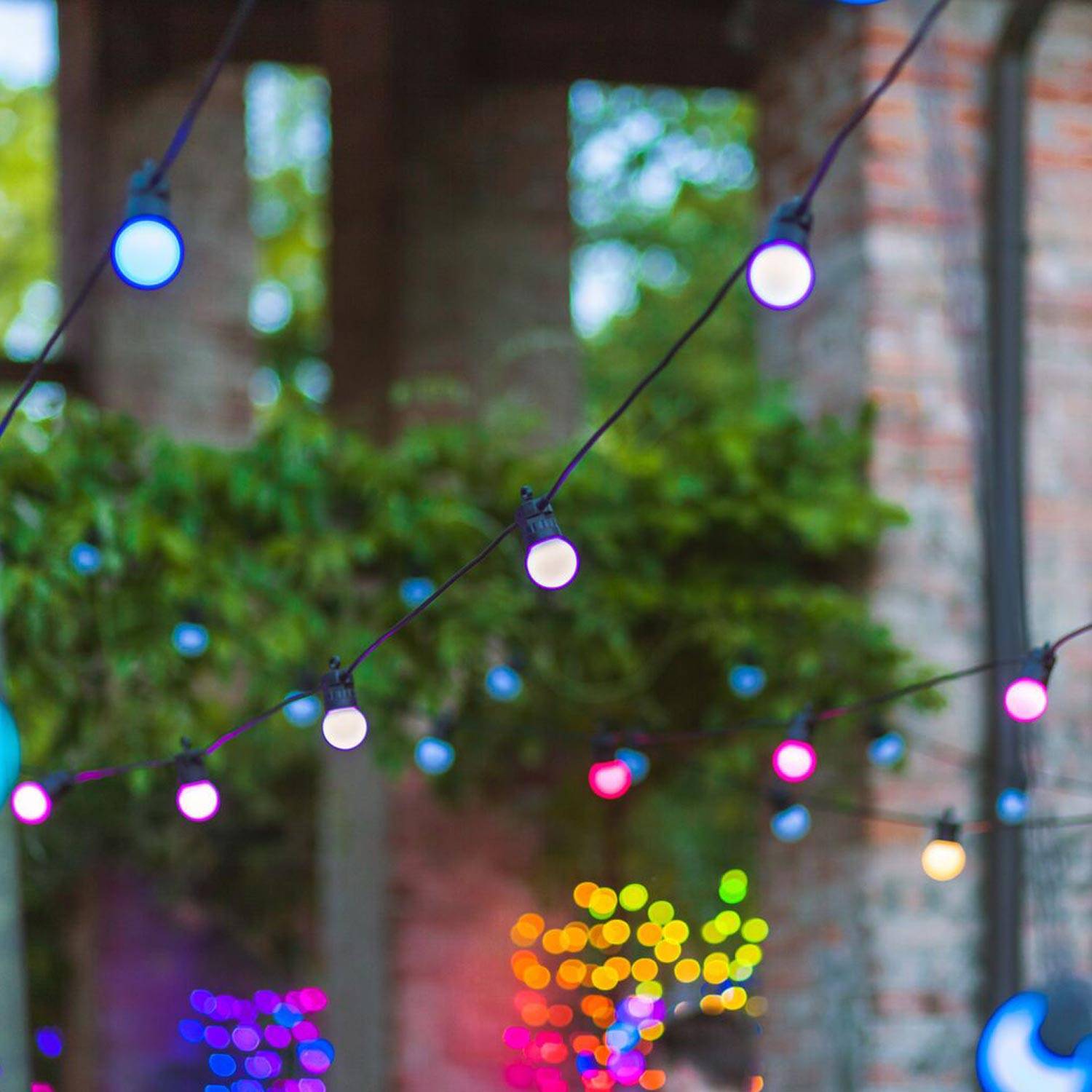 Twinkly festoon lights hanging in an outdoor space with different colours.