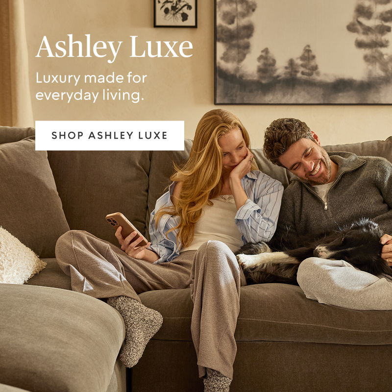 Lifestyle image featuring people relaxing on a luxury sofa with Ashley Luxe branding.