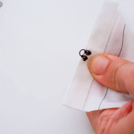 The eye of the hook and eye closure attached to the fabric edge