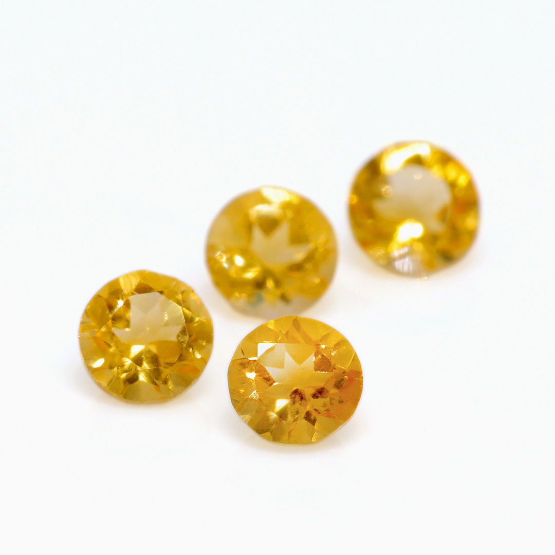 Four round yellow gemstones on a light background.