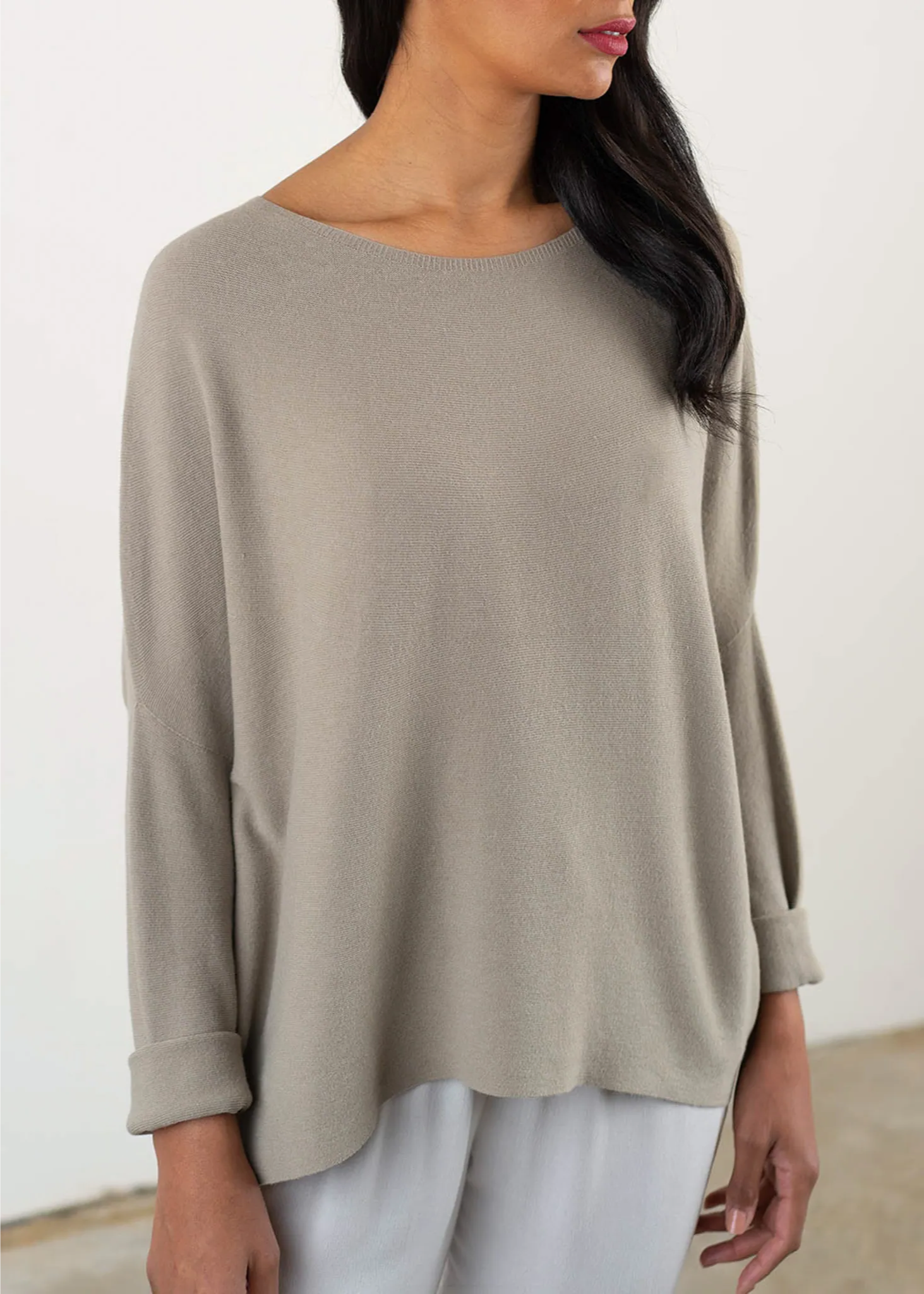 A model wearing a greige loose fitting sweater with a scoop neckline