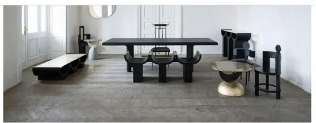 A modern room with various black furniture pieces arranged on a wooden floor.