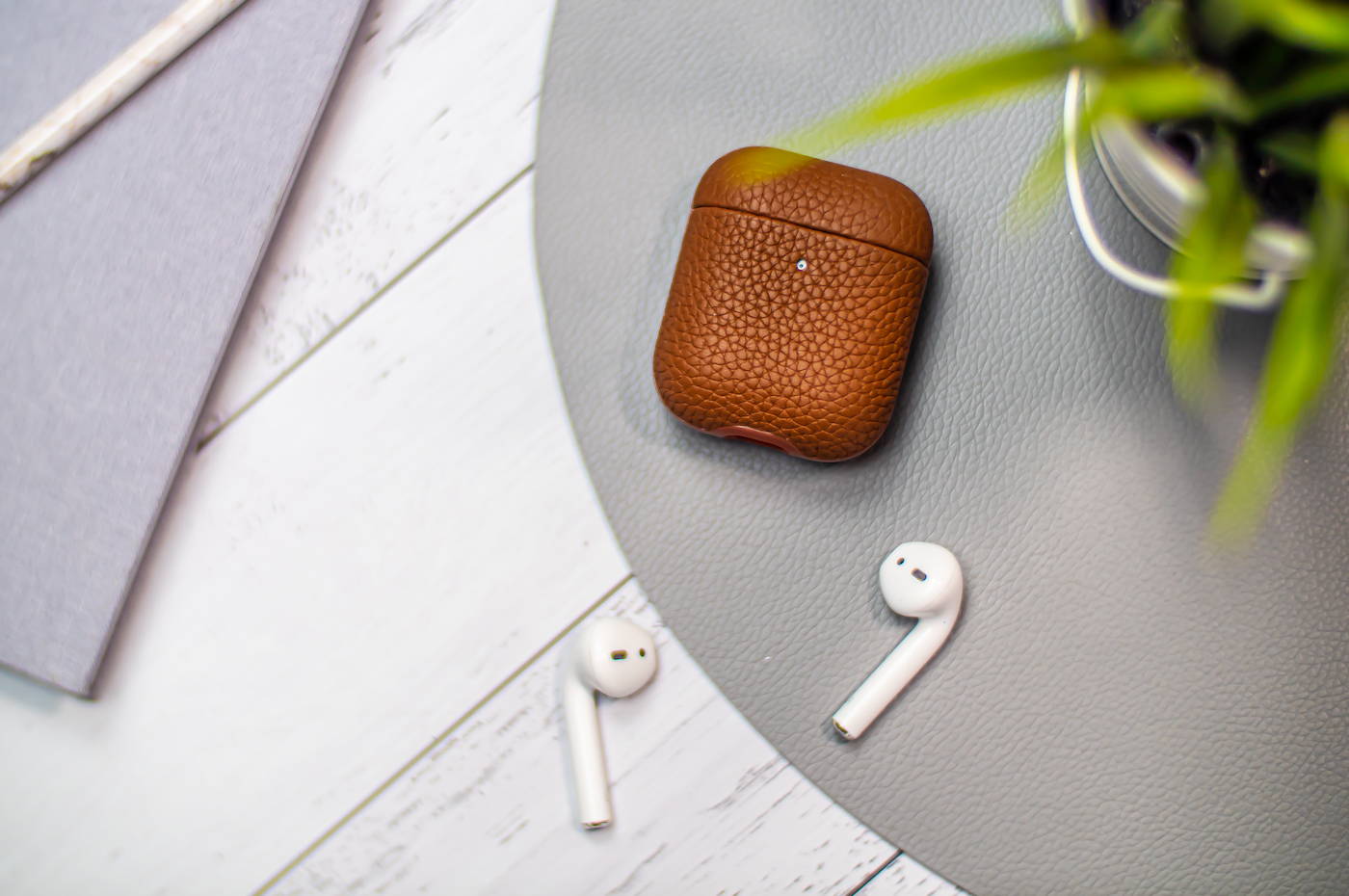 brown genuine leather airpods case laying flat on a grey table