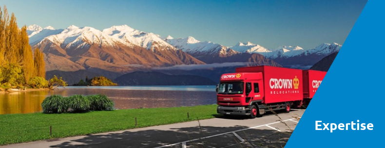 Red truck parked by a scenic lake and mountains.