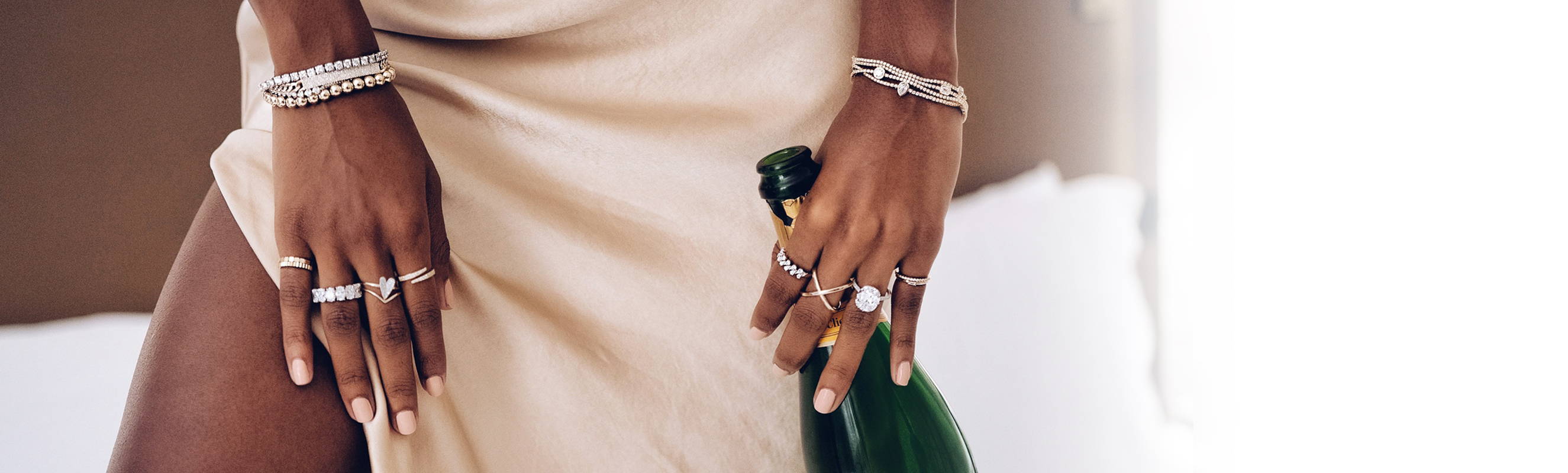 Model wearing Ring Concierge rings holding a bottle of champagne