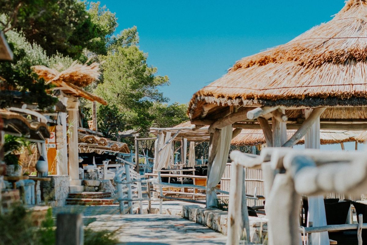 Tropical resort with thatched-roof structures and lush greenery under a clear blue sky.