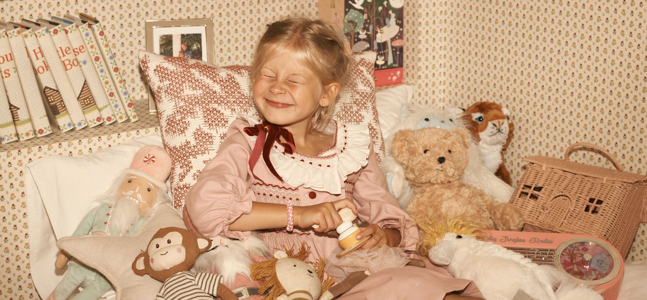 Smiling girl surrounded by stuffed animals and toys in a cozy setting.