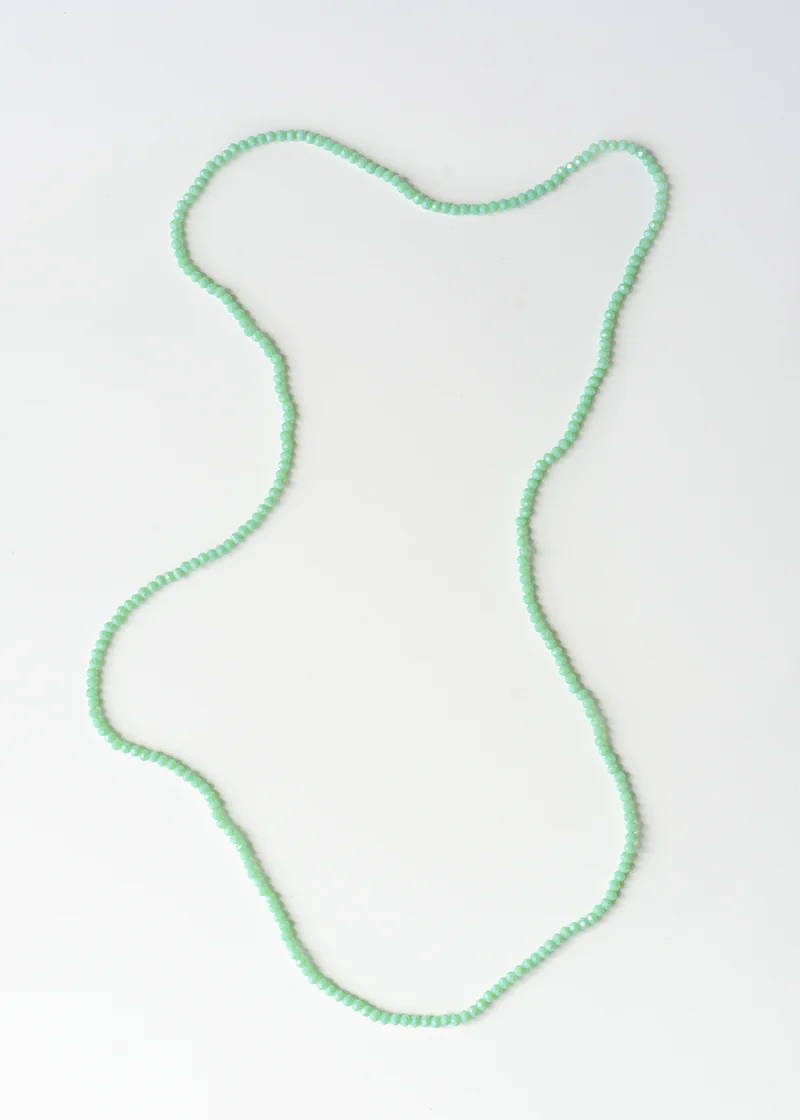 A pale green small beaded necklace on a white background