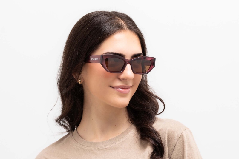 woman with heart shaped face wearing Riley Red sunglasses, geometric cat-eye frames, on a white background