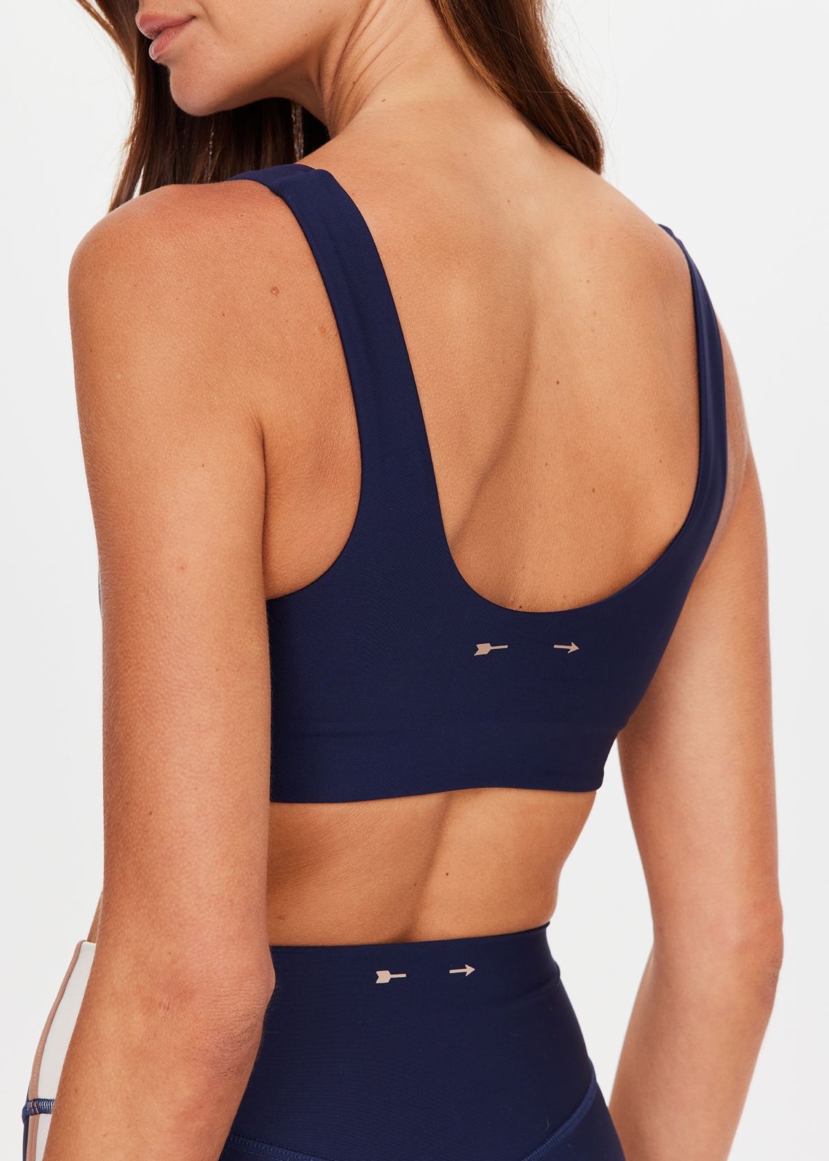 Woman wearing a navy sports bra and matching leggings, posing confidently.