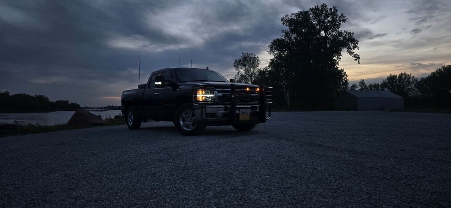 Front-three-quarter view Hunter's black 2012 Chevy Silverado at dusk on gravel lot with headlights brush guard and bed toolbox HornBlasters Safety Horn Air Horn Kit featured install gallery photo 1