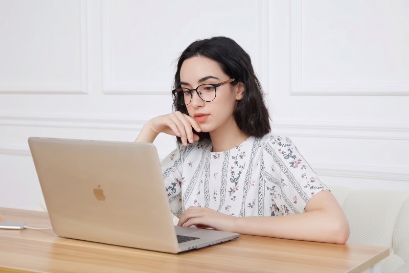 women wearing Honest Black eyeglasses while doing screen-heavy work on laptop