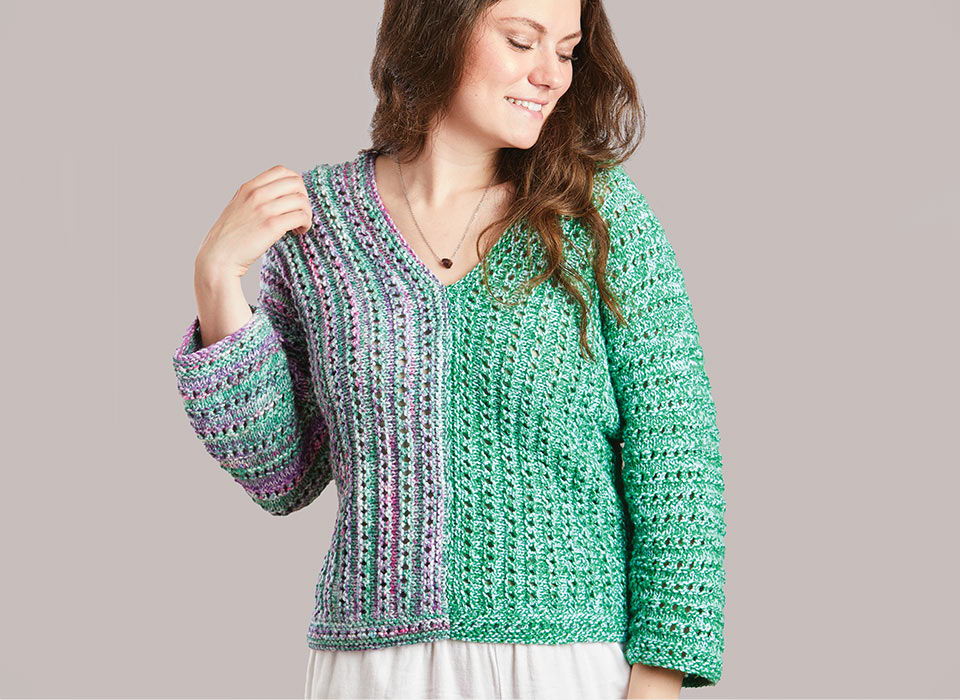 Woman wearing a colorful knitted sweater with a v-neck and long sleeves.
