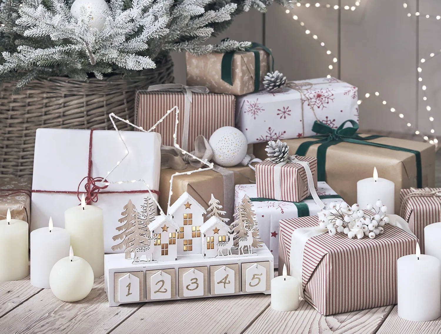 Presents, LED candles, star lights and a wooden advent calendar underneath a frosted Christmas tree.
