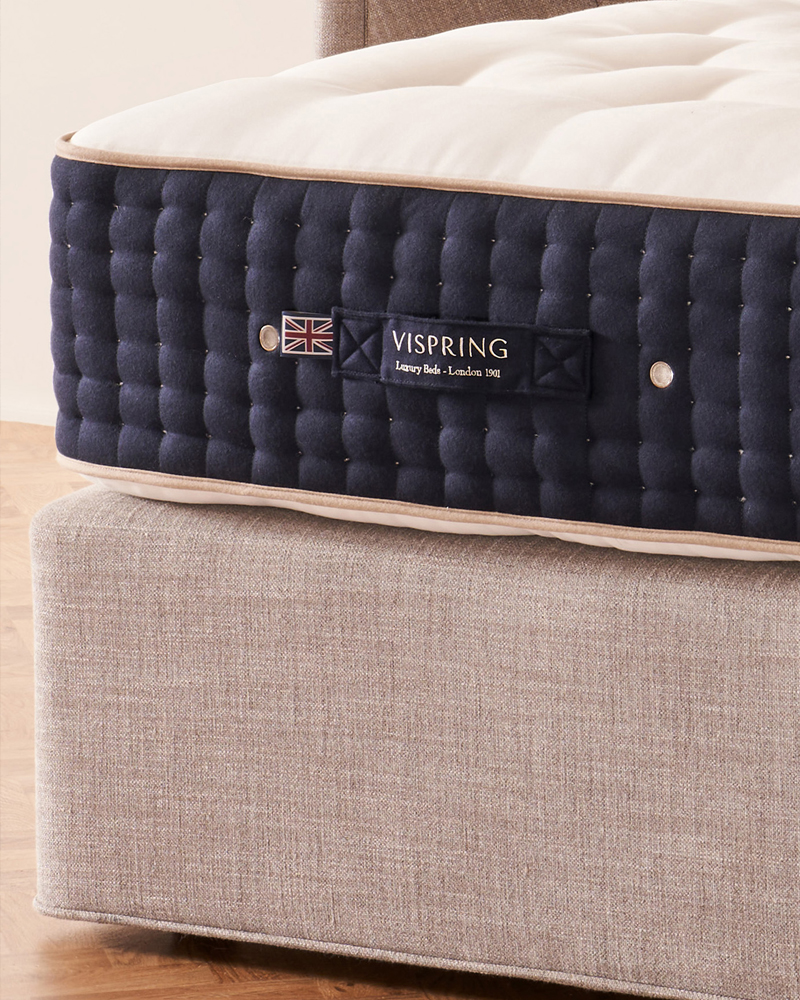 Close-up of a Vispring mattress on a fabric bed base.