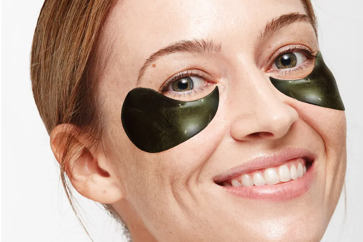 woman applying Depology black caviar hydrogel eye patches under the eyes
