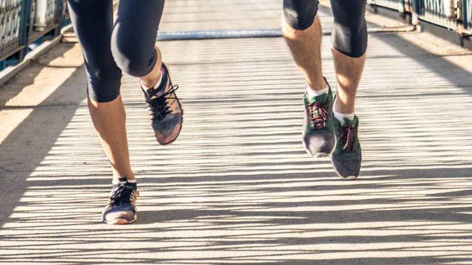 Man and woman running outdoors on bridge