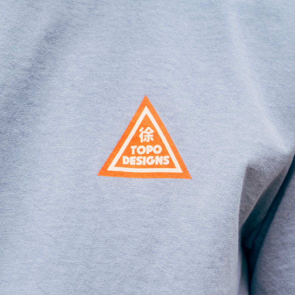 Logo of Topo Designs on a gray fabric.
