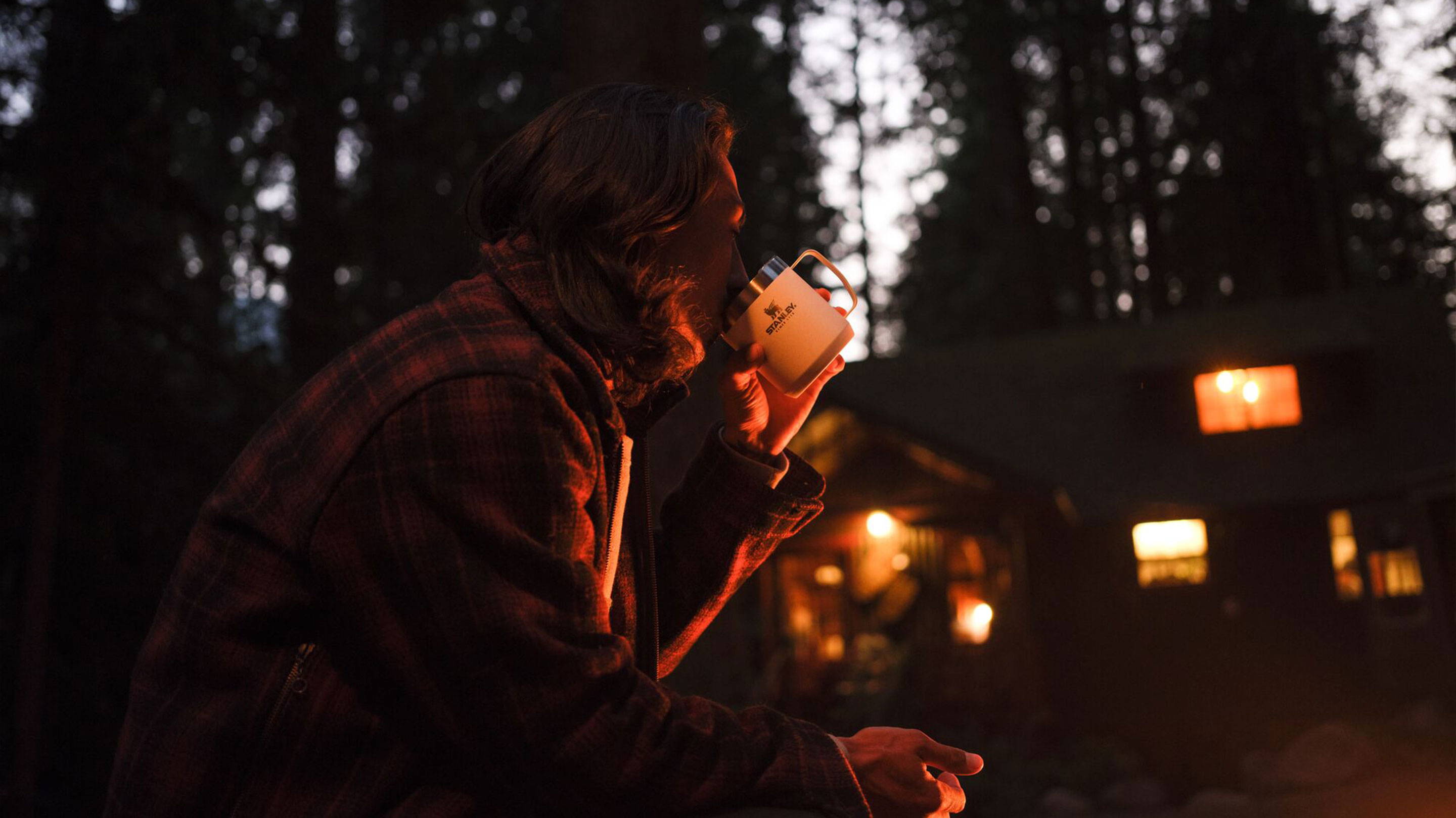 Man Sitting Outside At Duck Drinking From Stanley Mug