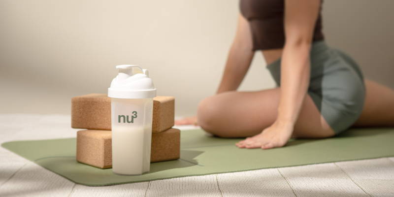 Frau beim Yoga mit Protein-Shake