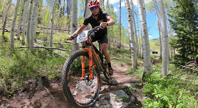 Person racing mountain bike on mountain trail. Photo Credit: Trekker Photo