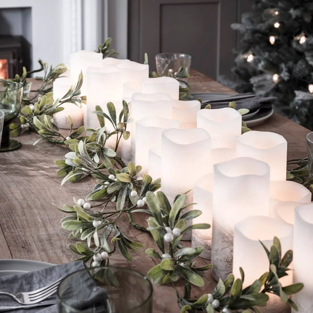 Christmas table setting lined with LED candles and a festive garland