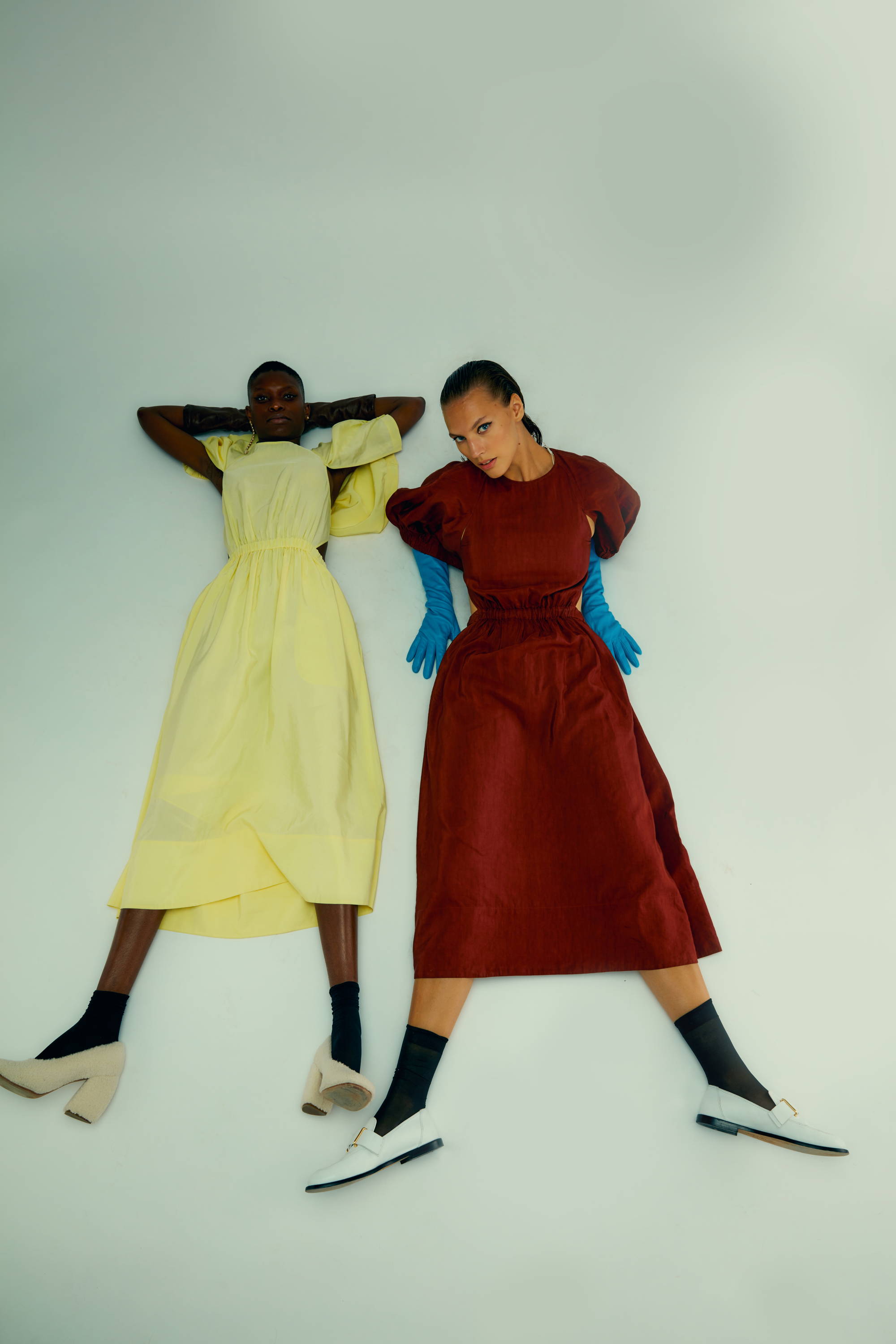 Two women lying on the ground in colorful dresses.