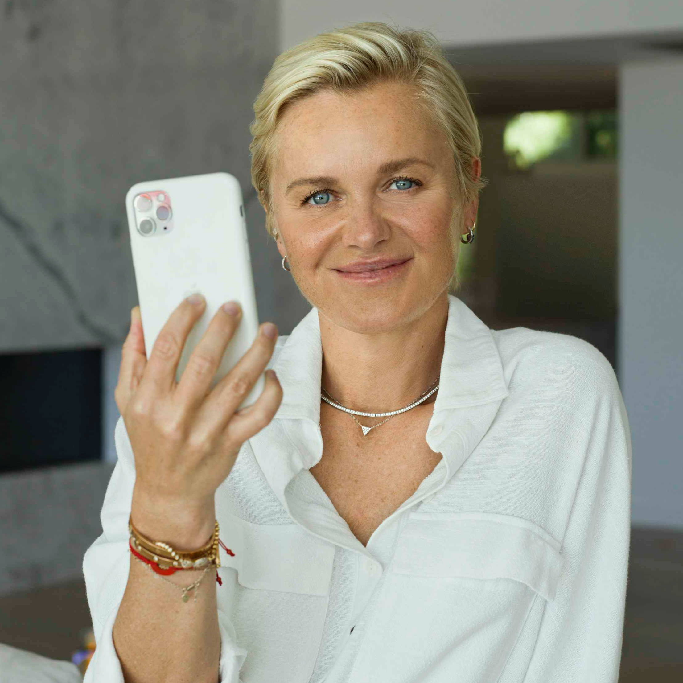 Dr Barbara Sturm holding a white iphone