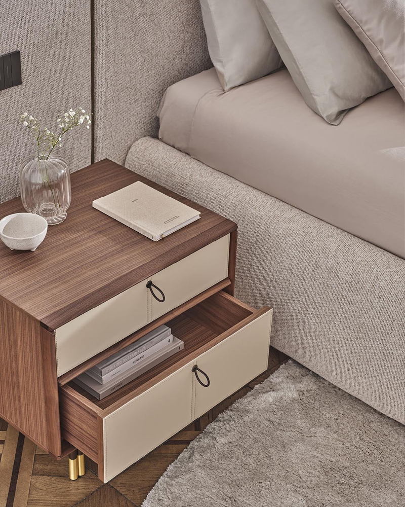 Wooden Bayus nightstand with drawers, a vase, and a book on top.