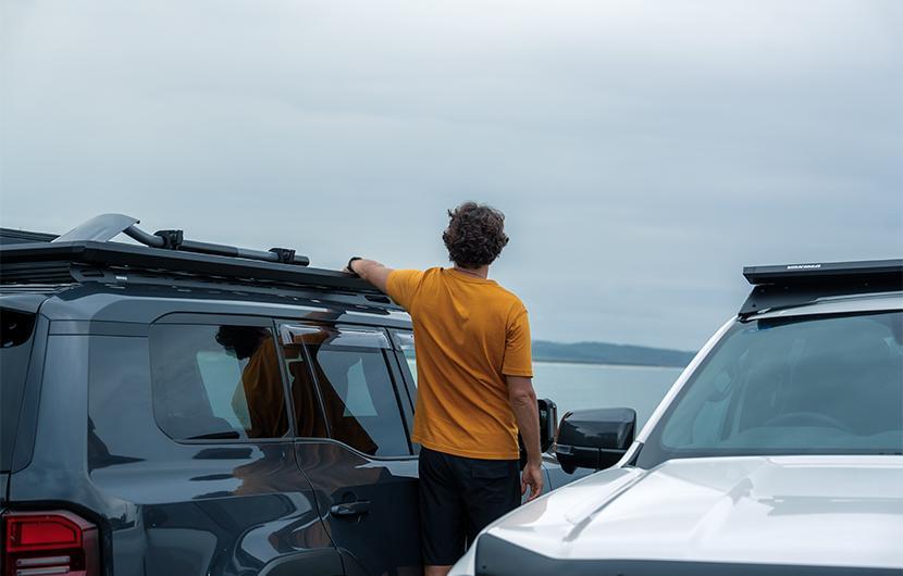 Two vehicles with roof rack platforms in front of the beach
