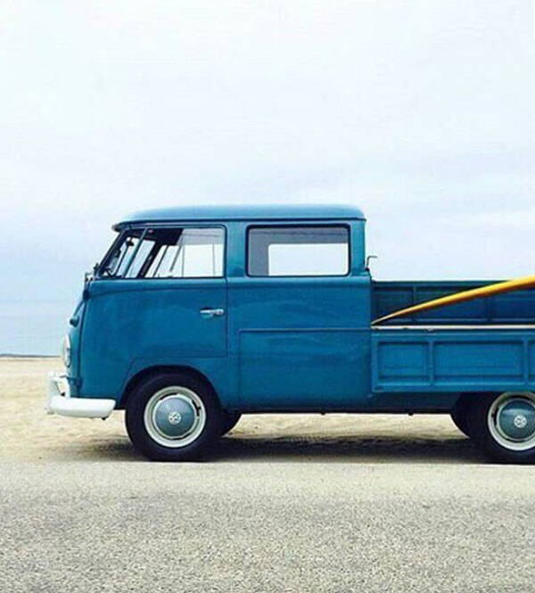 A mood image of a vintage blue van carrying a yellow surf board.
