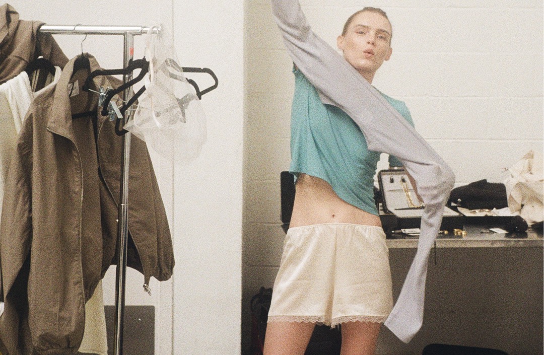 girl in dressing room putting on sweater