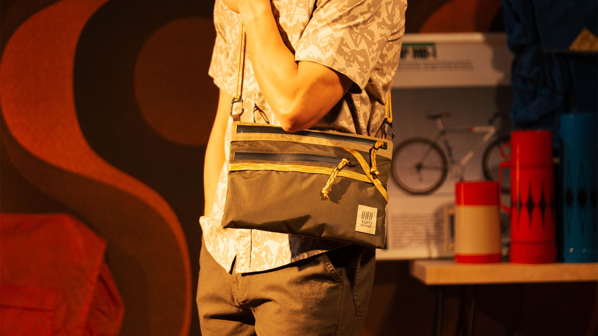 Person holding a bag, standing on stage with colorful background.