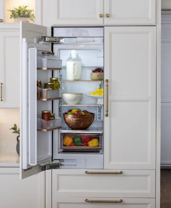 Open refrigerator filled with fruits, vegetables, and containers on shelves.