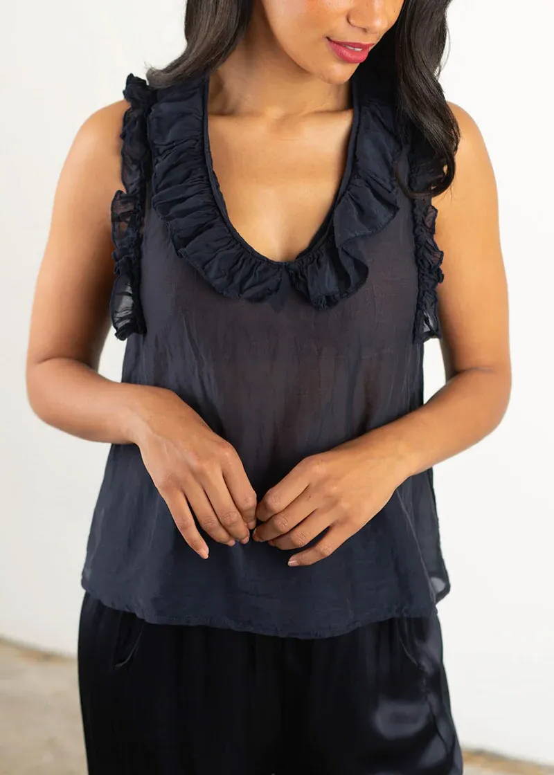 A model wearing a dark blue sleeveless top with frill detailing around the neck and arm holes
