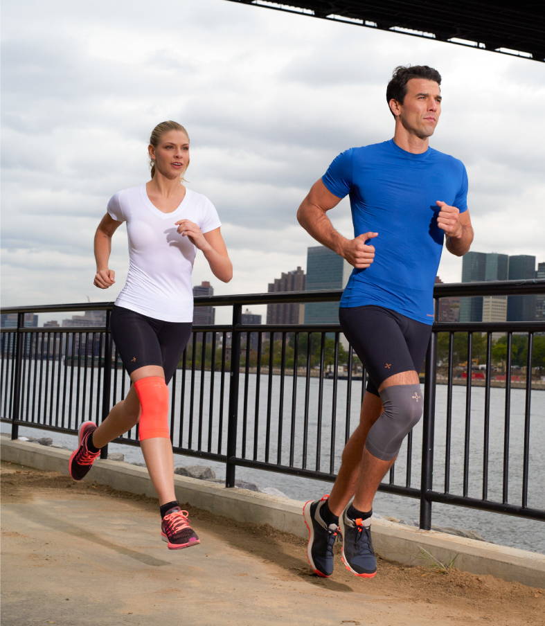 A man and a woman running in Tommie Copper compression sleeves