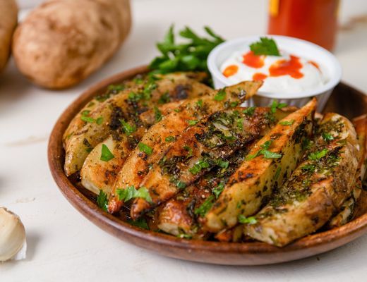 Plate of grilled stuffed flatbreads with yogurt sauce and herbs.