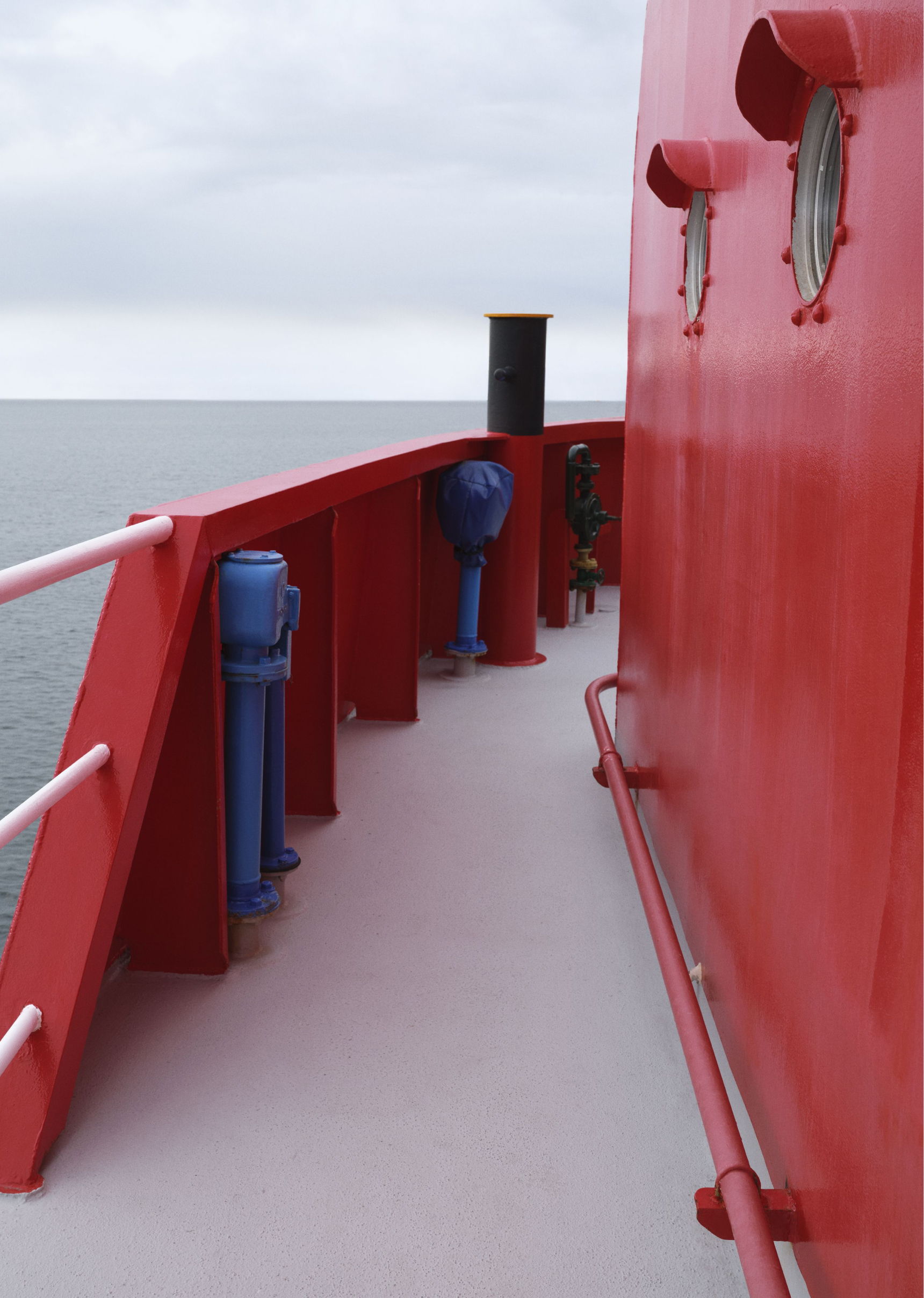 Red ship deck with blue fixtures and ocean in the background.